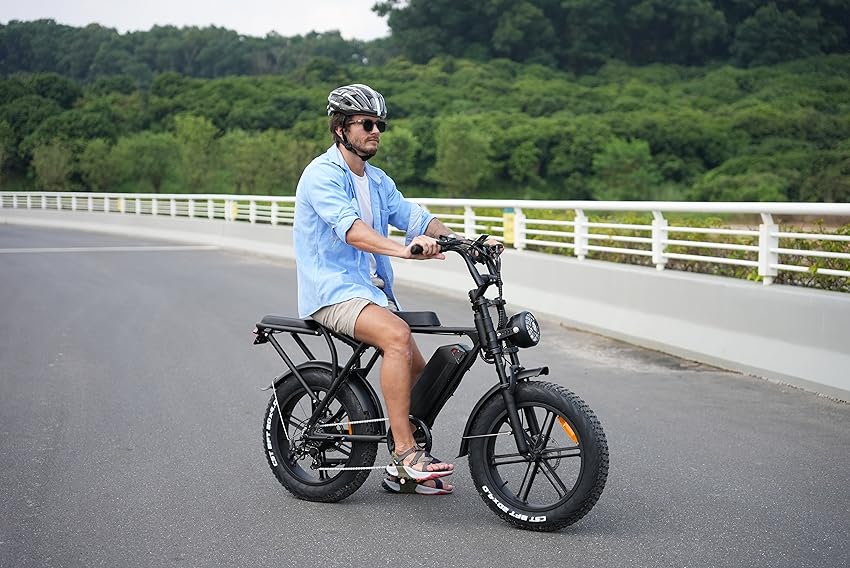 Man sitting on a fatbike on the road, enjoying a scenic outdoor ride.